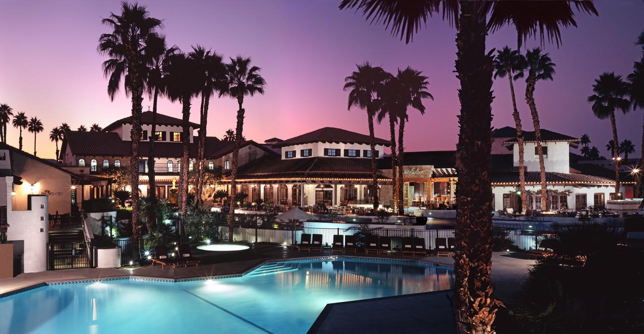A group of palm trees with a building in the background
