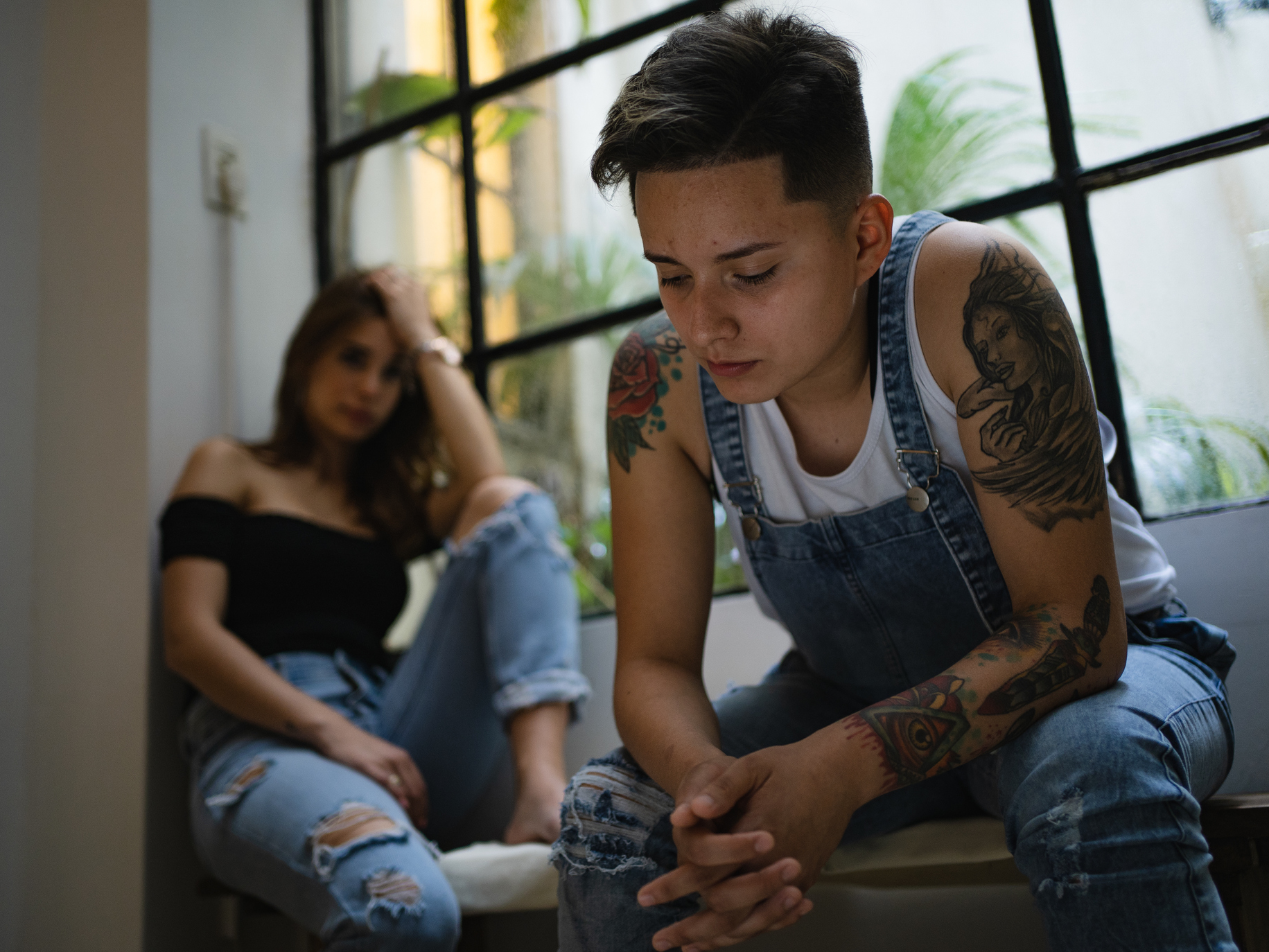 A man and woman sitting next to a window